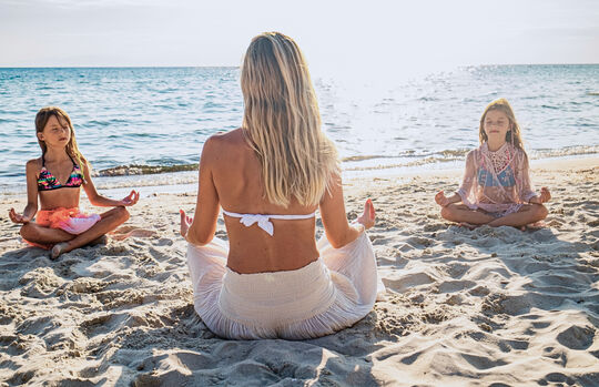 Mom with two young daughters on the beach at Pareus Beach Resort – sunny moments enjoying yoga and relaxation by the sea.