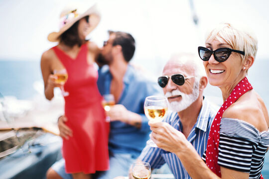 A younger and an older couple laughing and enjoying a sunny day by the sea at Pareus Beach Resort – unforgettable family moments.